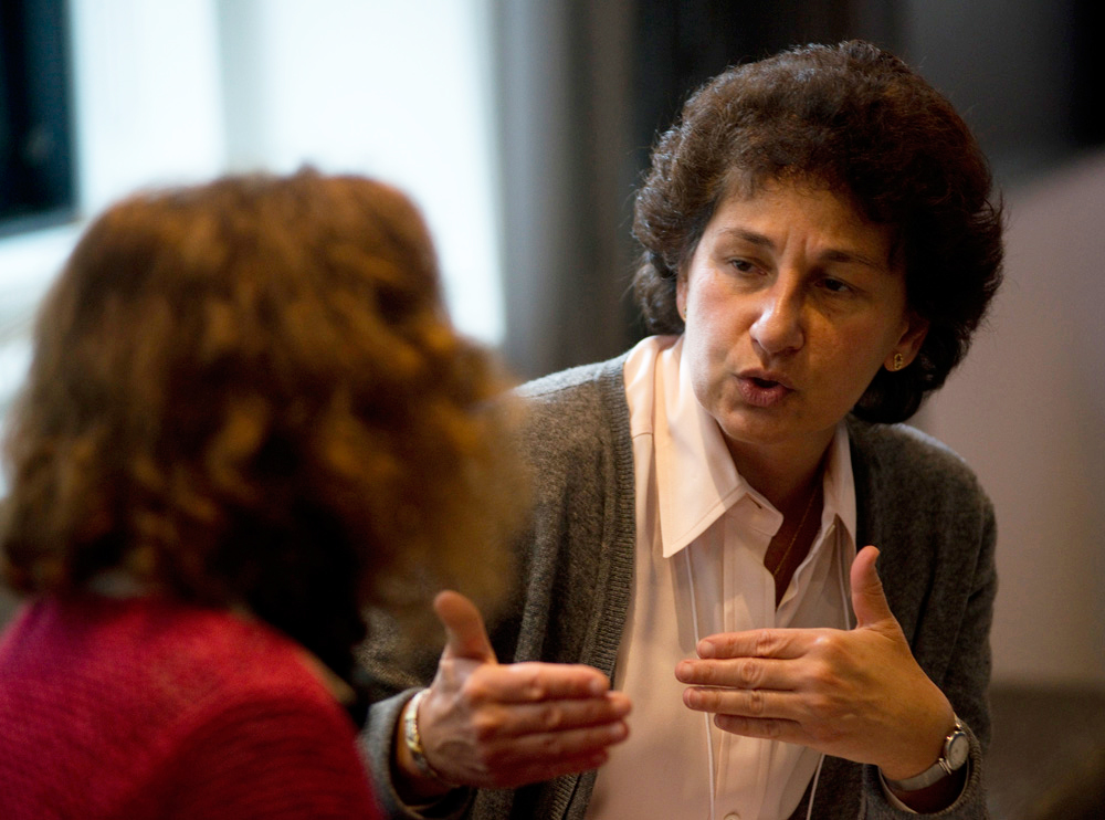 Two people sitting and talking with each other as one person gesticulates with both hands