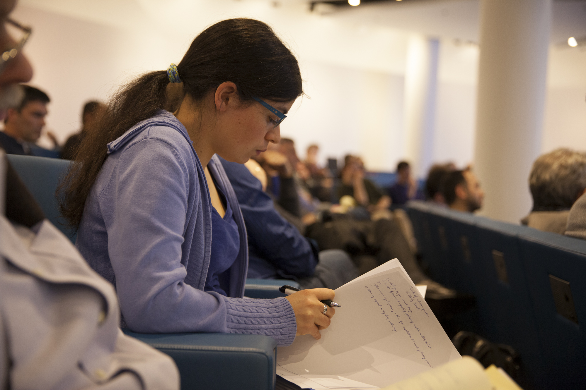 Woman sitting in a lecture hall while flipping a notebook page