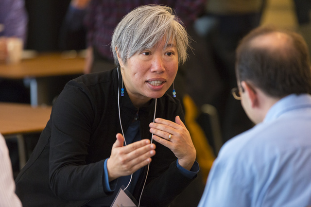 Andrea Liu leaning over to talk to sitting man