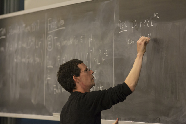 Larry Guth writing on a chalkboard