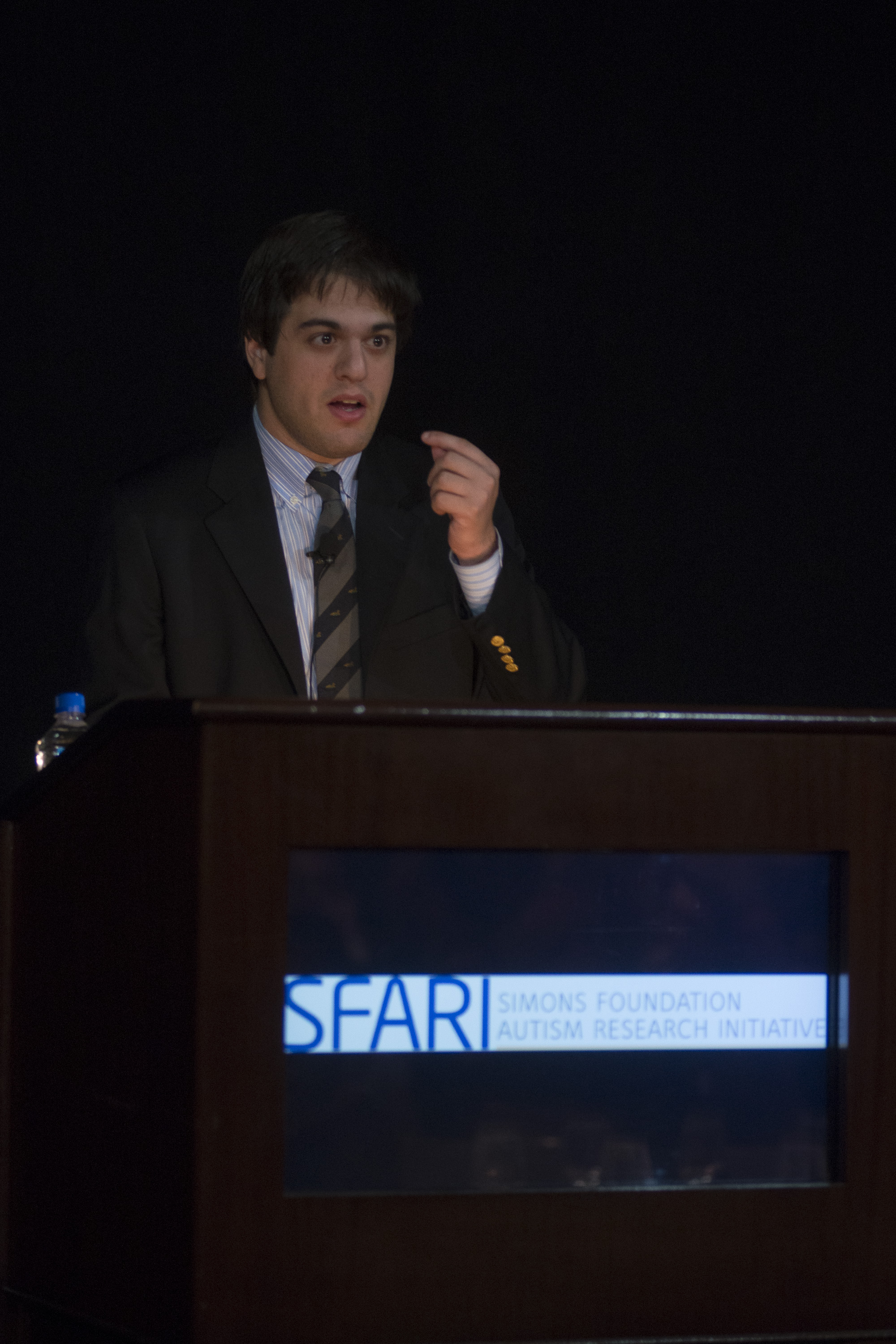 Man standing behind a lectern that says SFARI Simons Foundation Autism Research Initiative