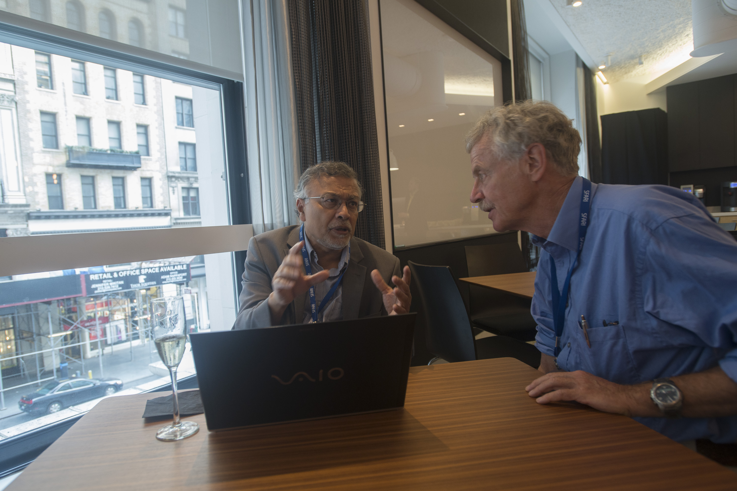 Two men at a table together with a computer