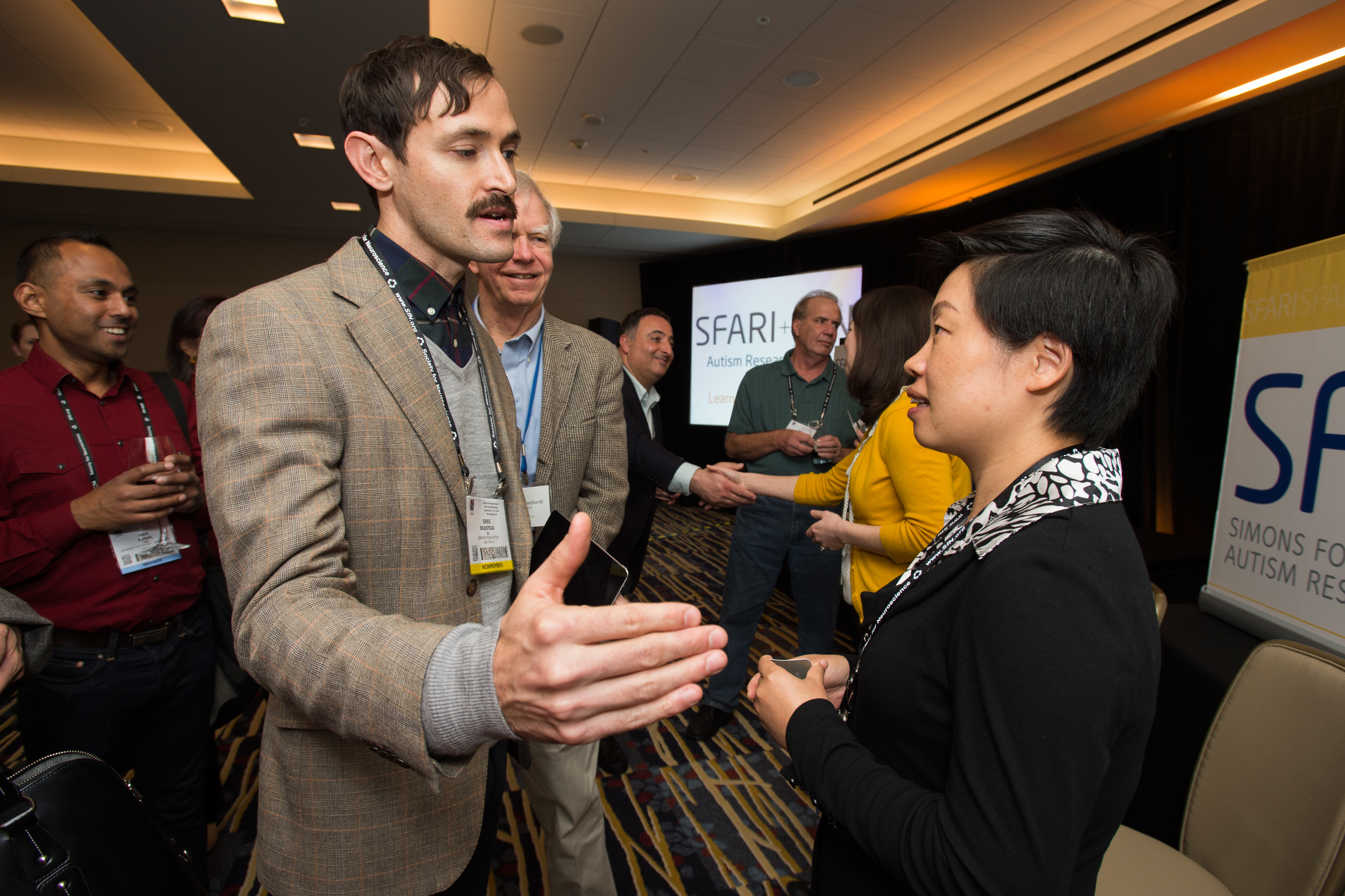 Woman and man talking as someone stands behind the man and watches