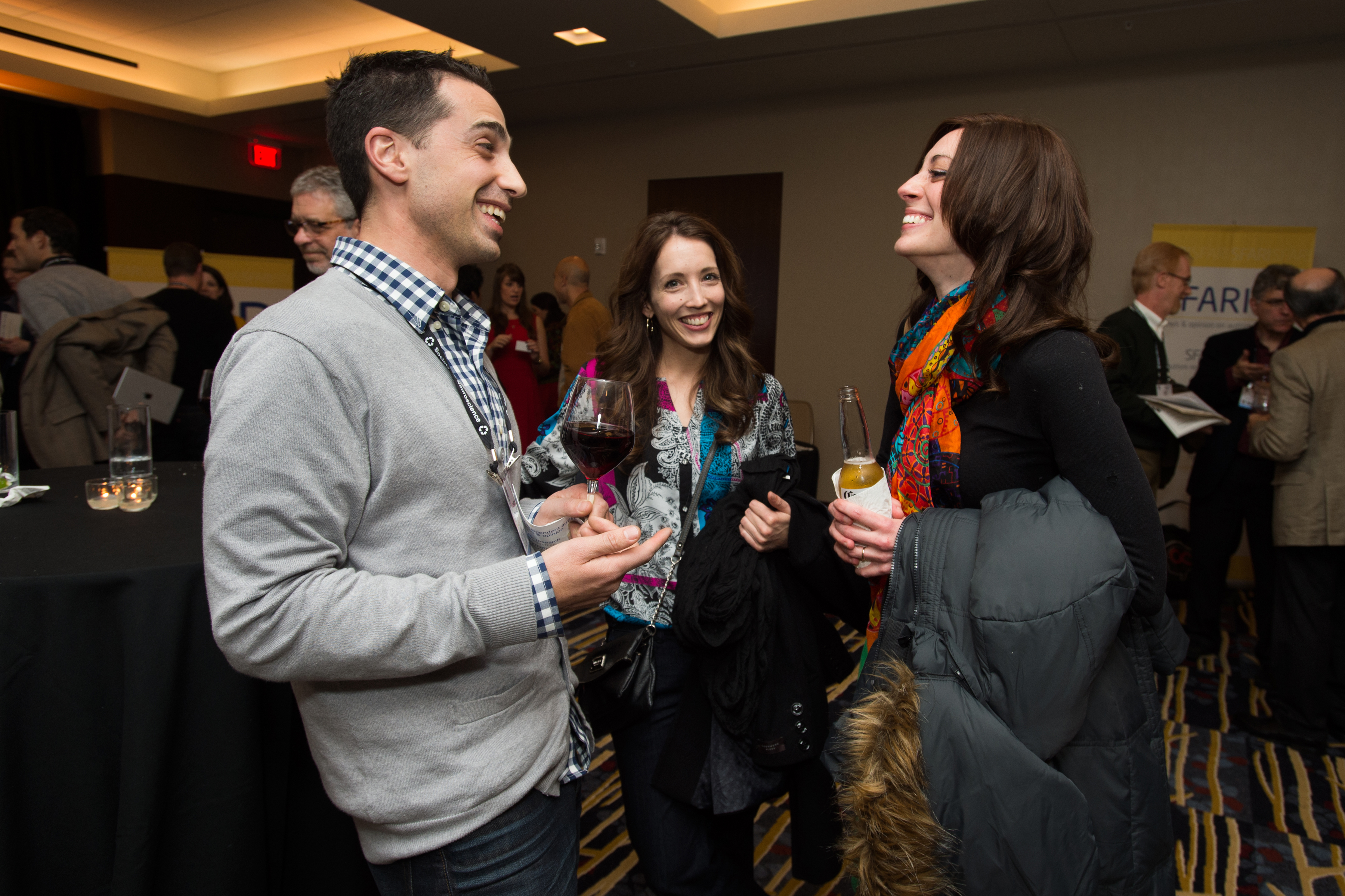 Three people standing and smiling as they hold alcoholic beverages