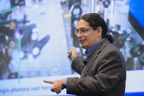 Man using a clicker to point to a screen and pointing to the front with his left hand