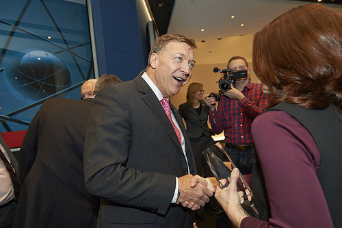 Man talking to a woman as a videographer behind him records them
