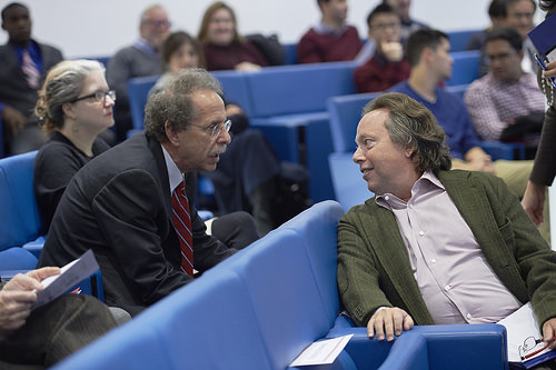 Two men sitting in a lecture hall talking