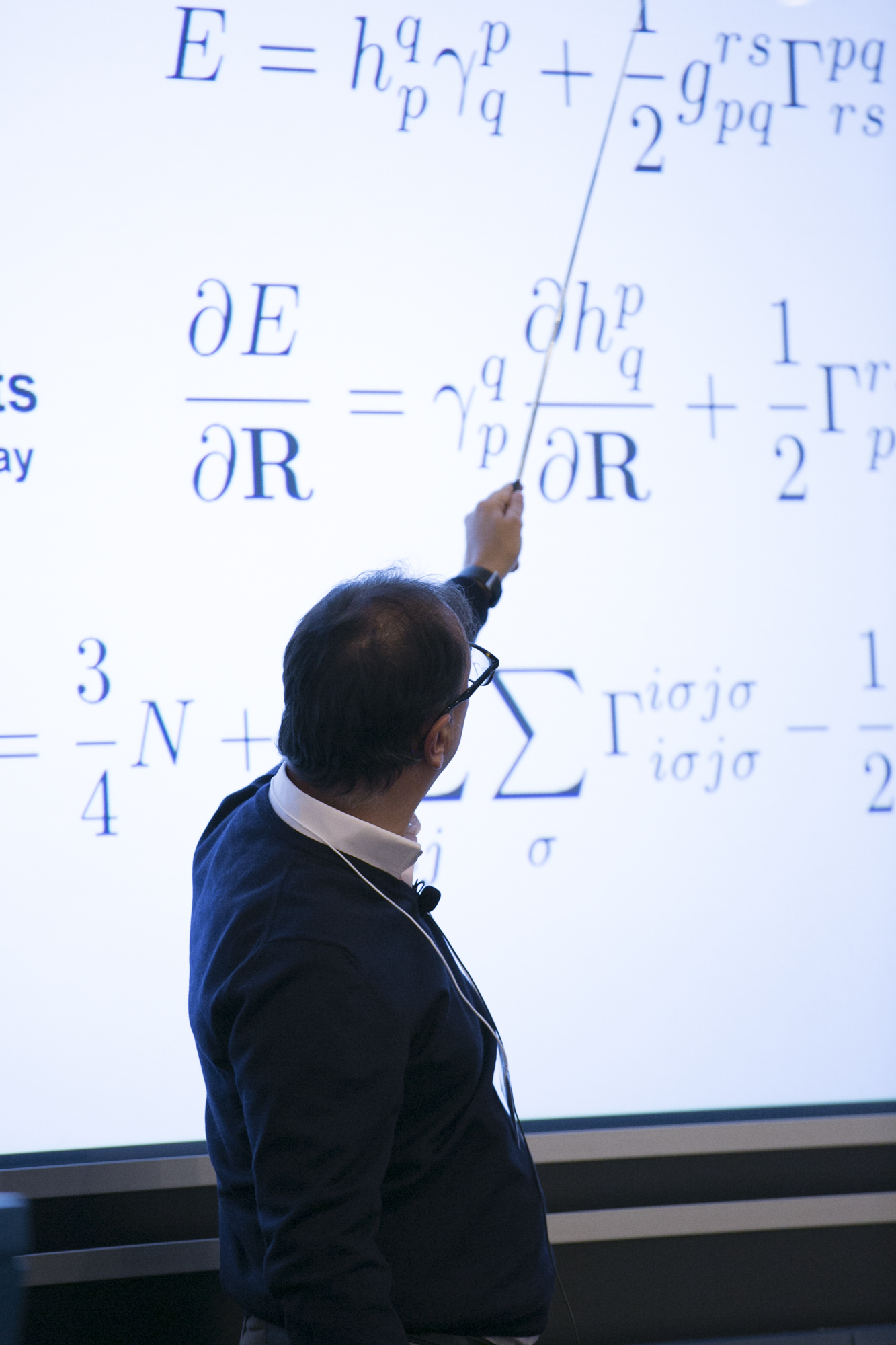 Man using a stick to point to math on a presentation
