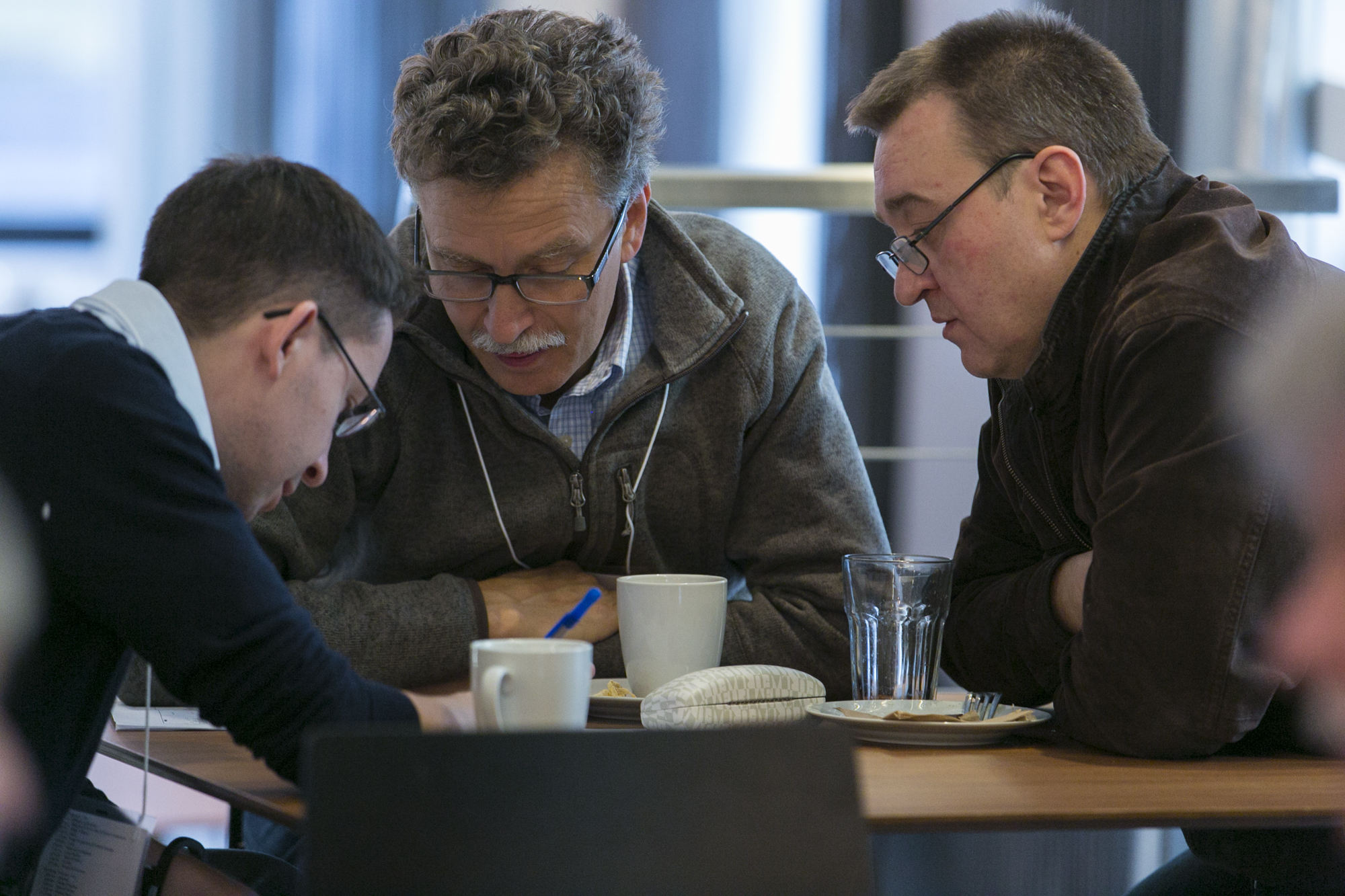 Three men sitting and collaborating at a table
