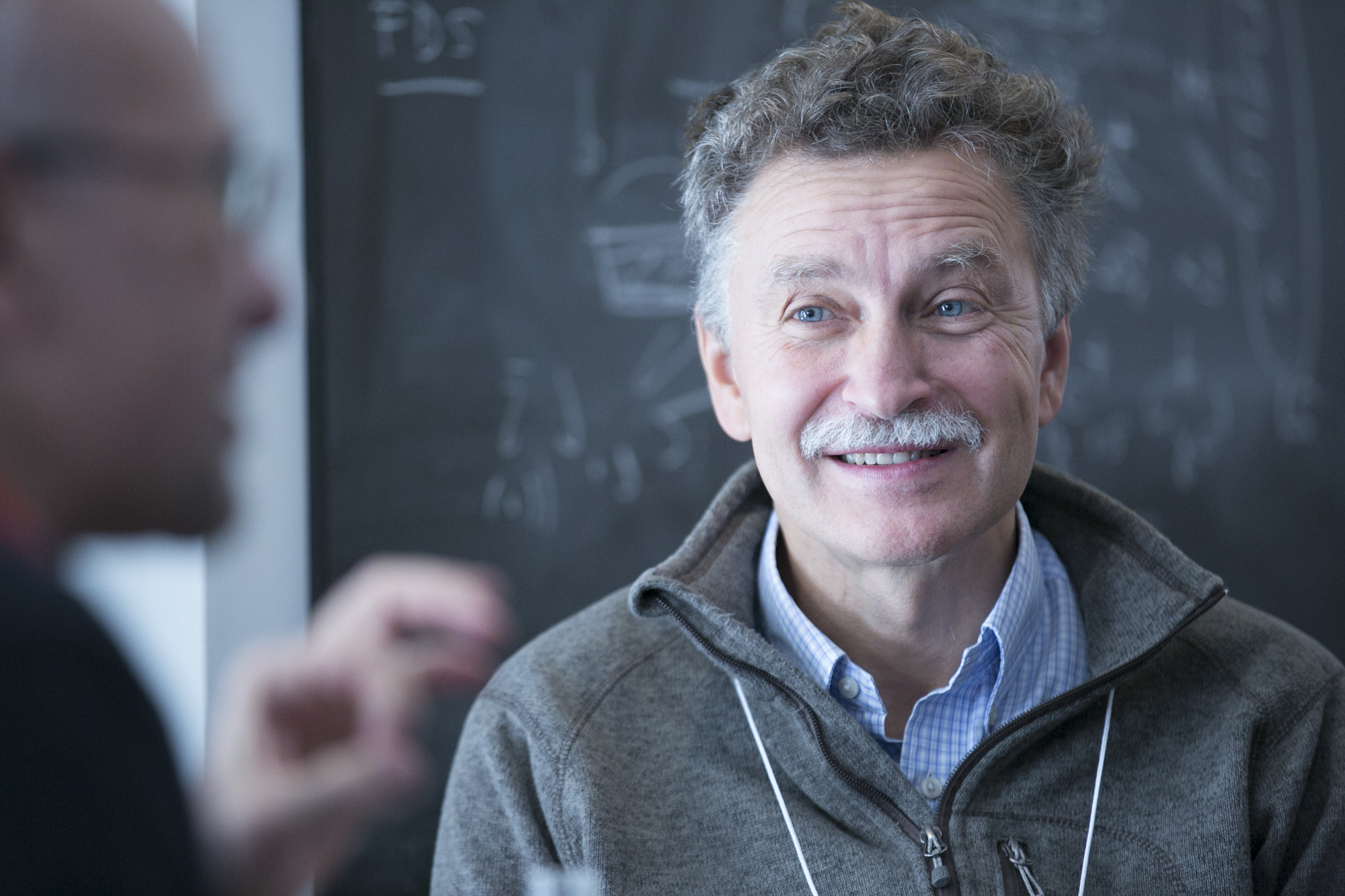 Man sitting in front of a blackboard