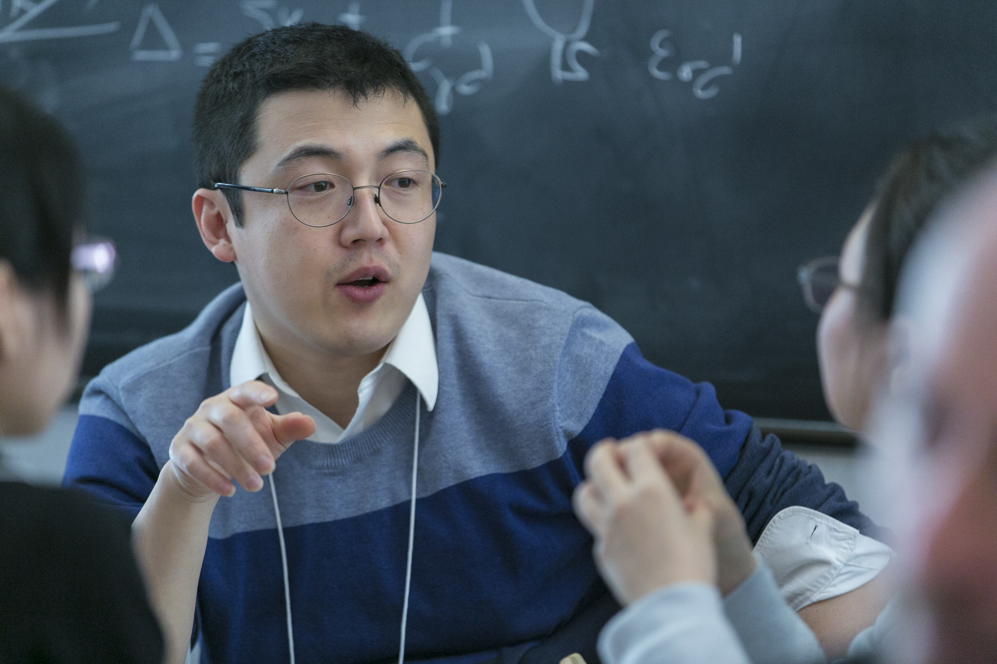 Man sitting at a table and talking as he points with his right hand
