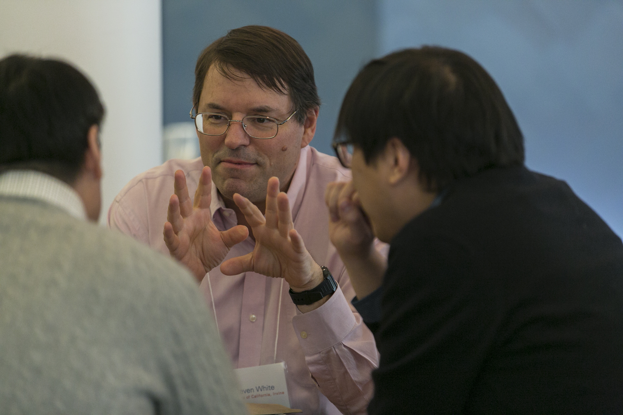 Three men sitting at a table together and talking