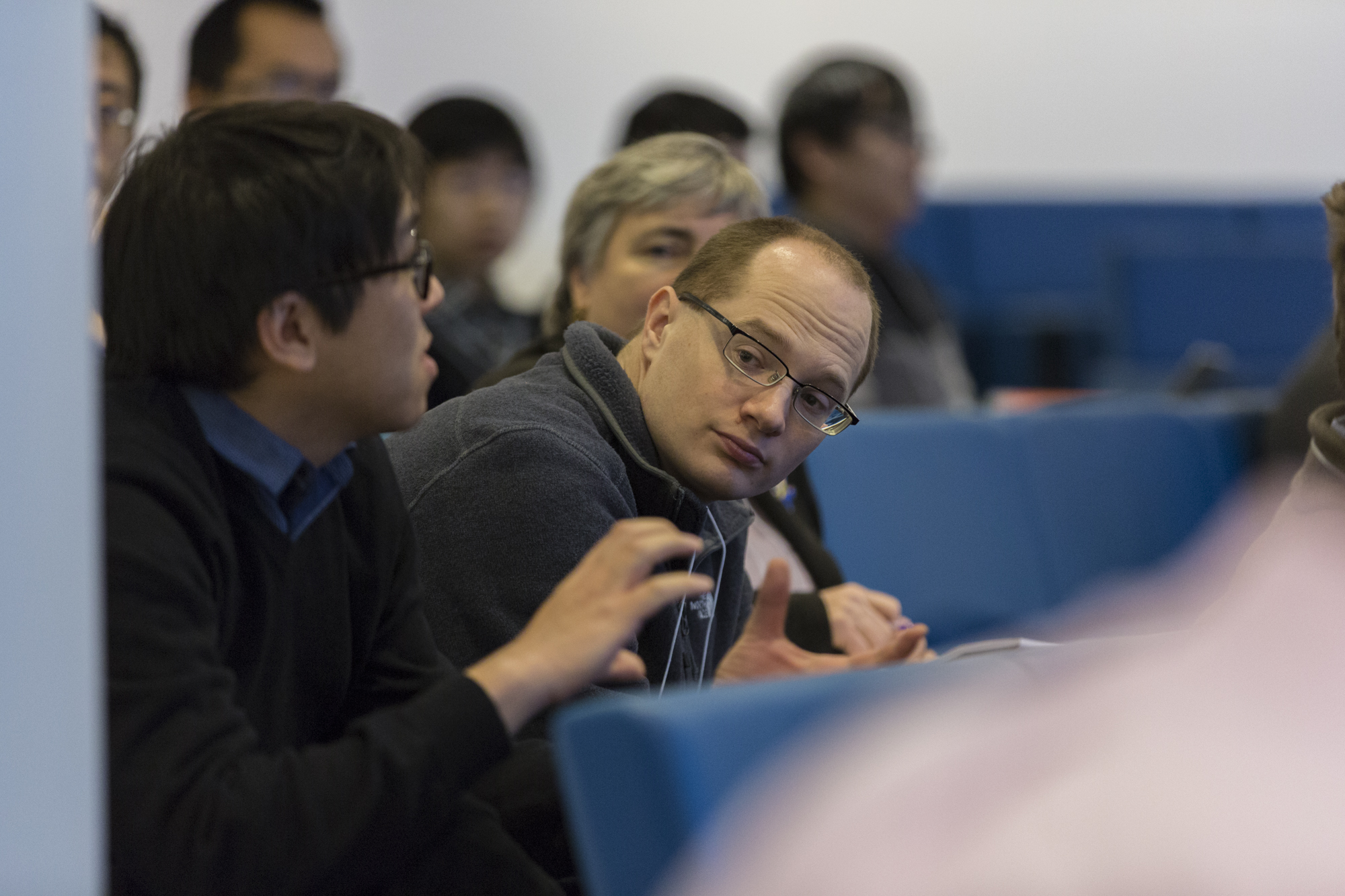 Man gesticulating as he sits in a lecture hall