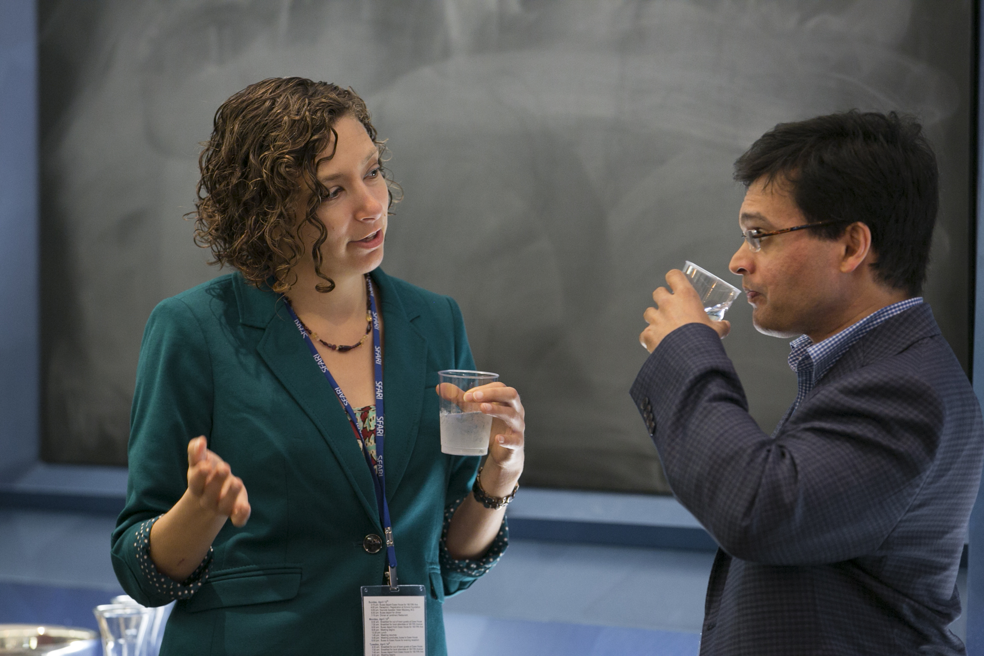 Woman and man standing and talking in front of a chalkboard