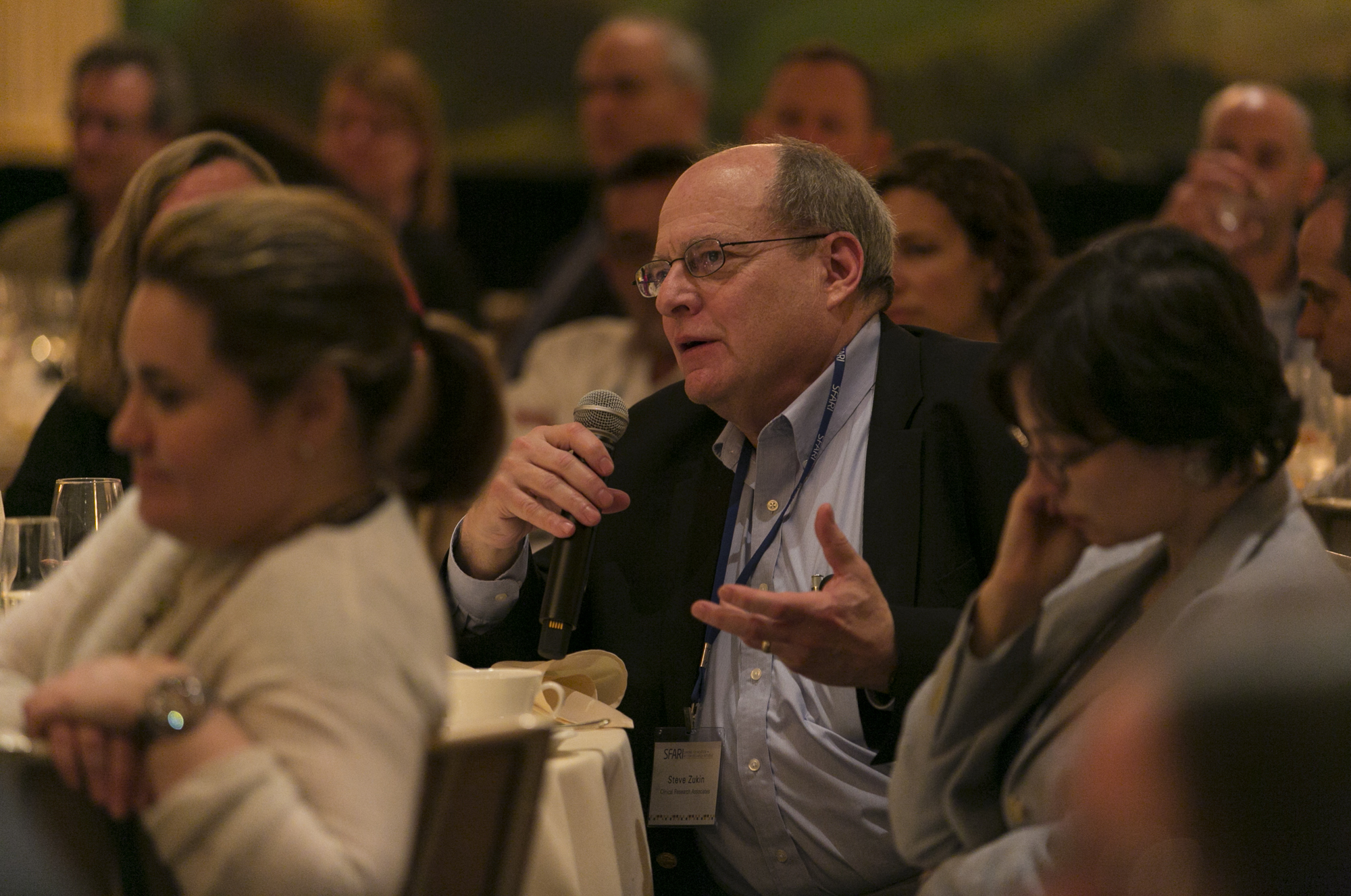 Man sitting at a table while talking into a microphone
