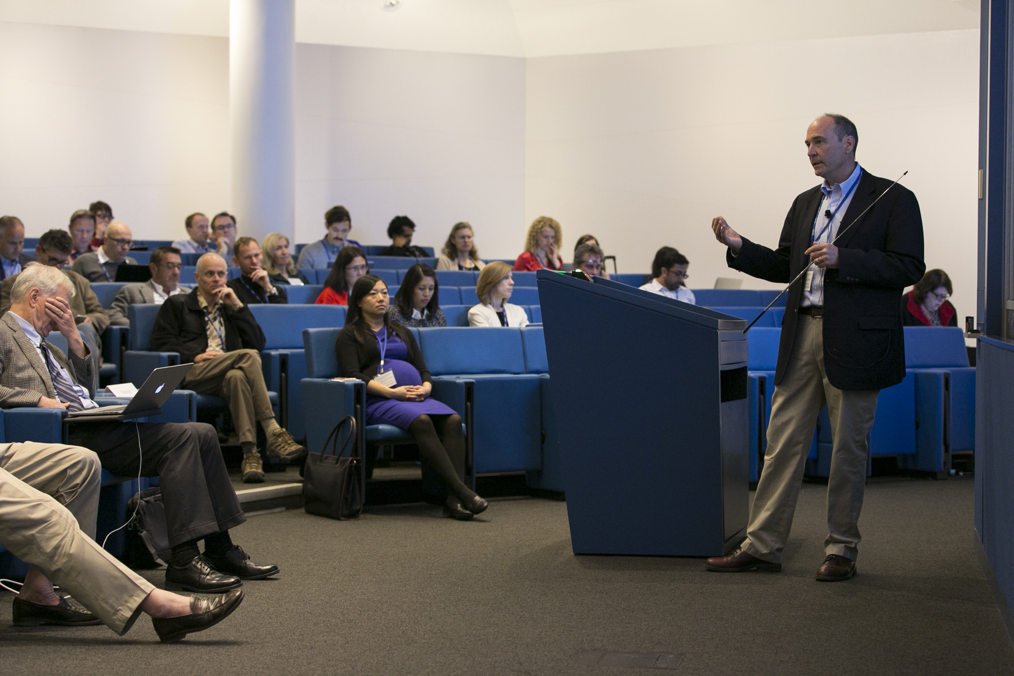 Man standing in front of a half-full lecture hall and talking