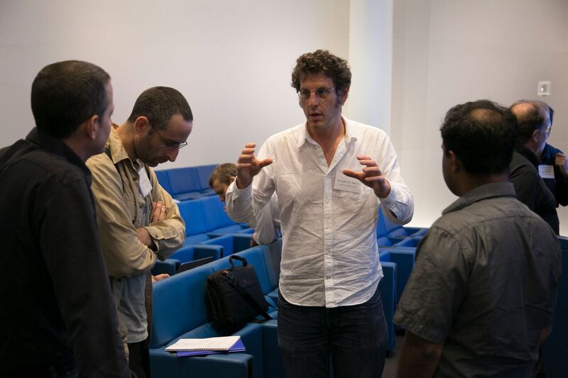 Five people standing in a lecture hall and talking