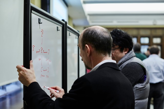 Man writing on whiteboard as another person watches