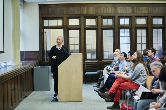 Man standing behind lectern as a classroom of people watch