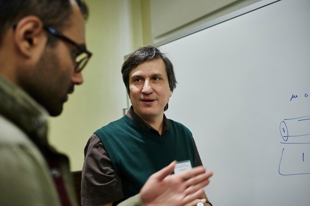 Two men standing by whiteboard and talking
