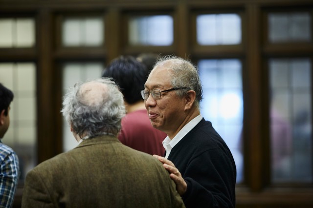 Man standing and smiling while touching someone's shoulder