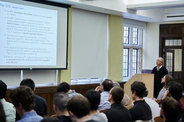 Man presenting a slideshow to a class, titled The SYZ conjecture
