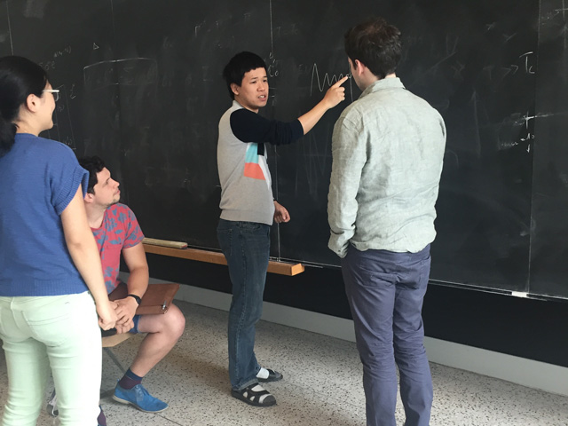 Man pointing to a chalkboard while three people watch