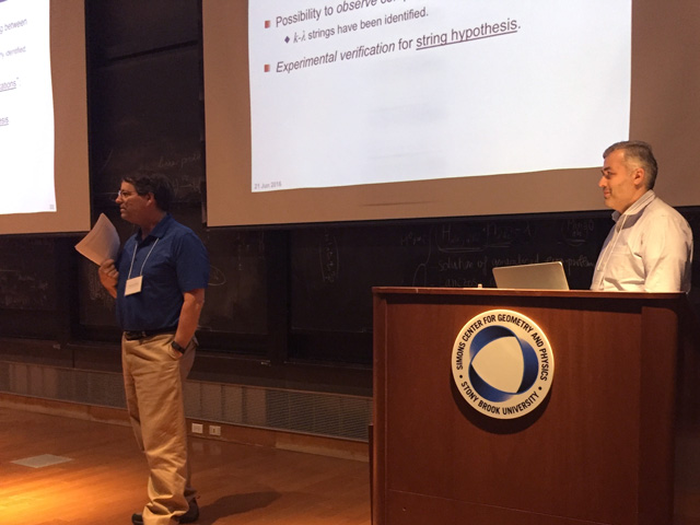 Two men standing in front of a lecture hall, presenting a slideshow that says 