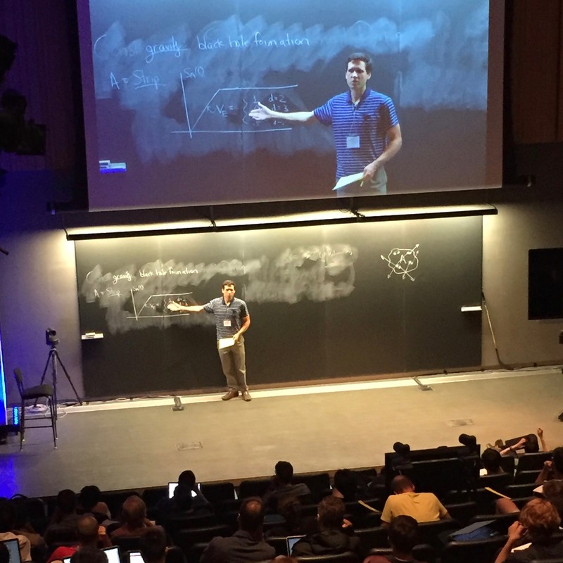 Man pointing to a hand-drawn graph on a chalkboard