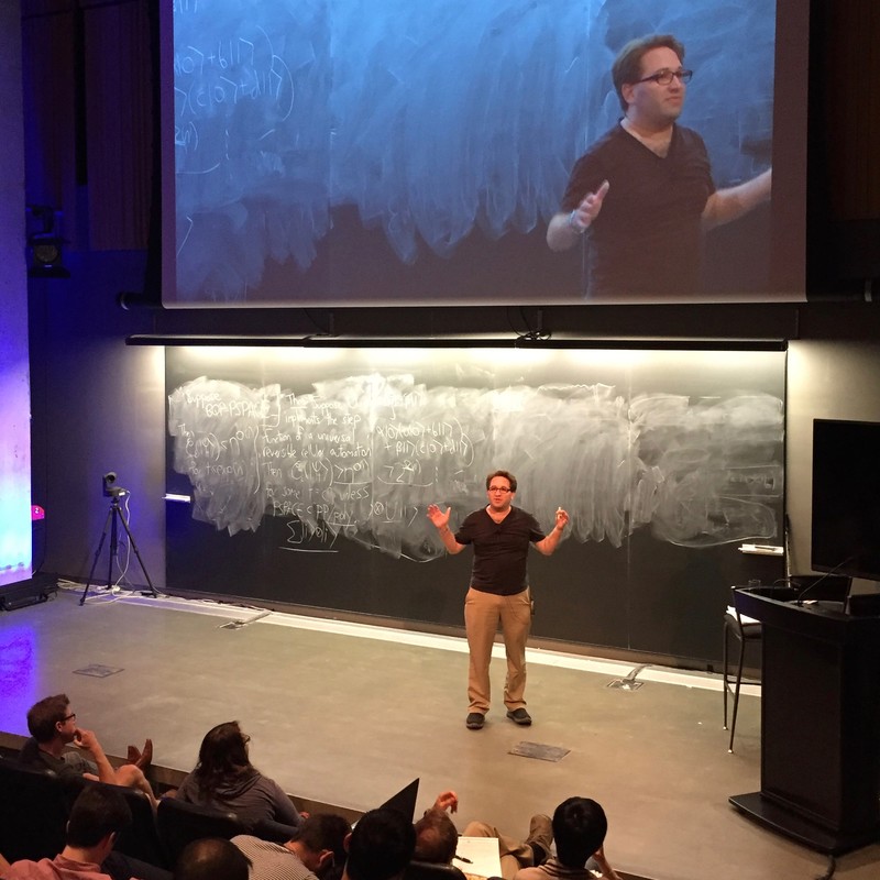 Man talking in front of a chalkboard with math