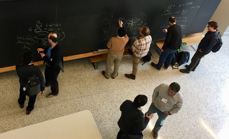 Top-down image of eight people standing and talking in a hallway