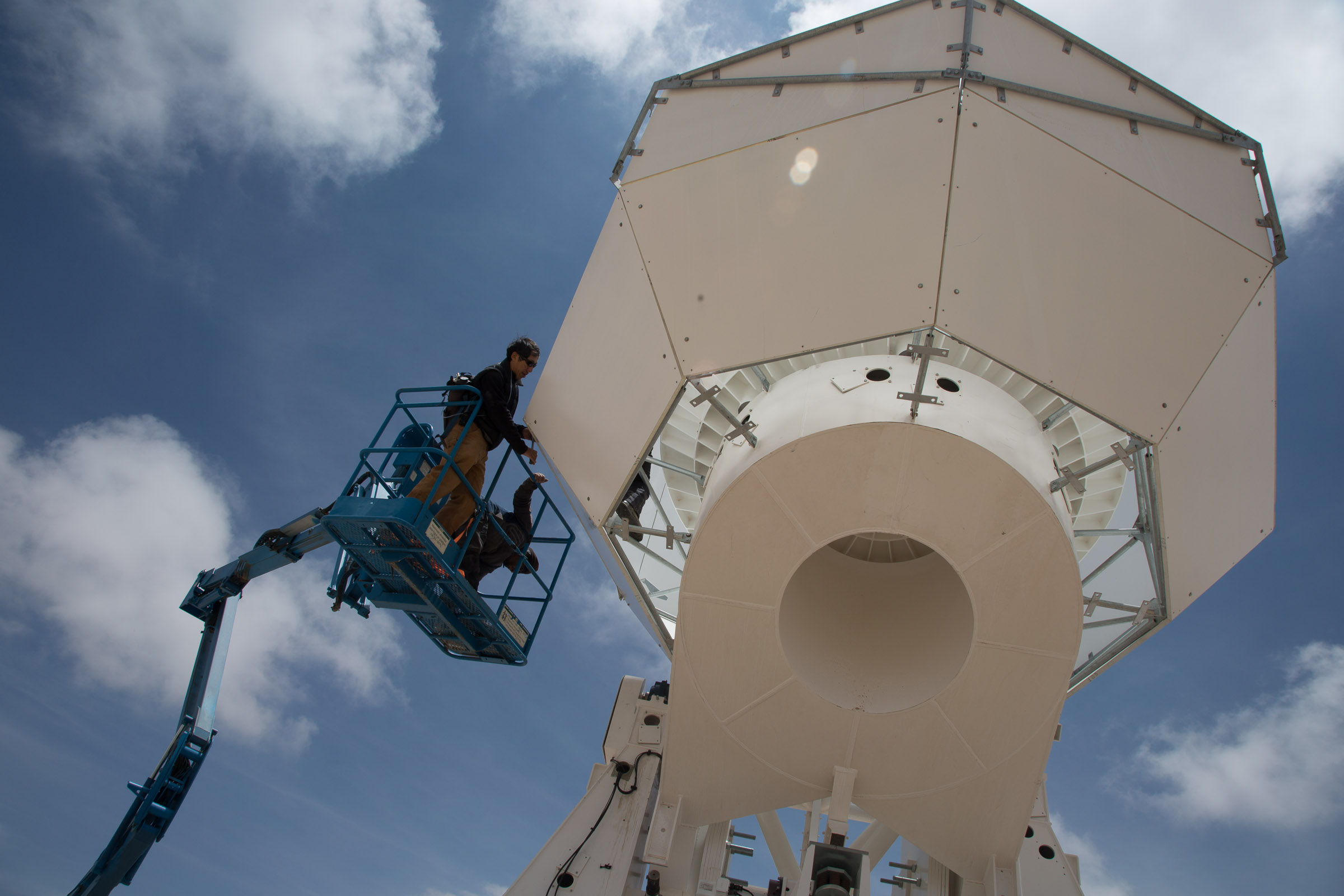 Man in a crane working on the Simons Observatory