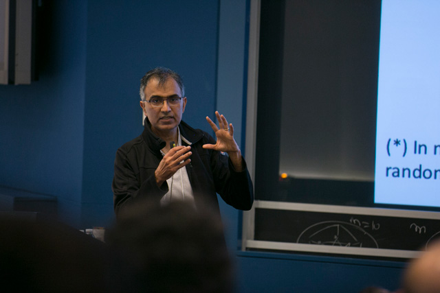 A man gesticulating with both hands up while talking to a lecture room
