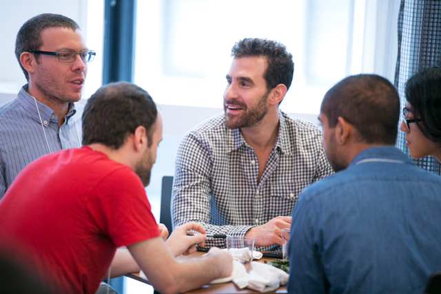 Five people sitting around a table talking