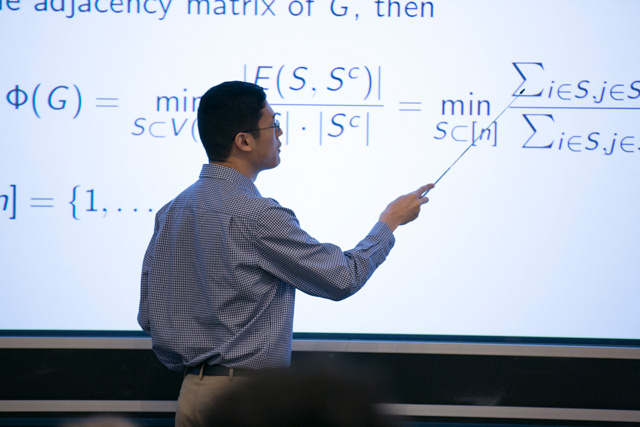 Man pointing a stick to a summation on a glowing screen