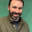 Scott McKinley in front of a green chalkboard