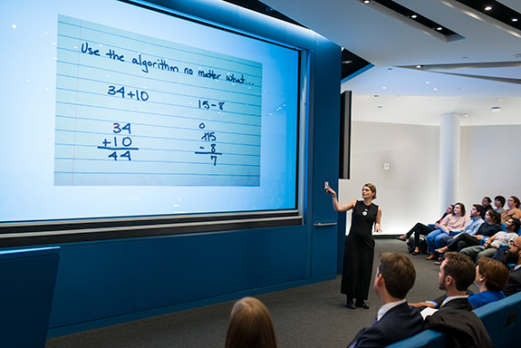 Woman presenting a projected slideshow that says 