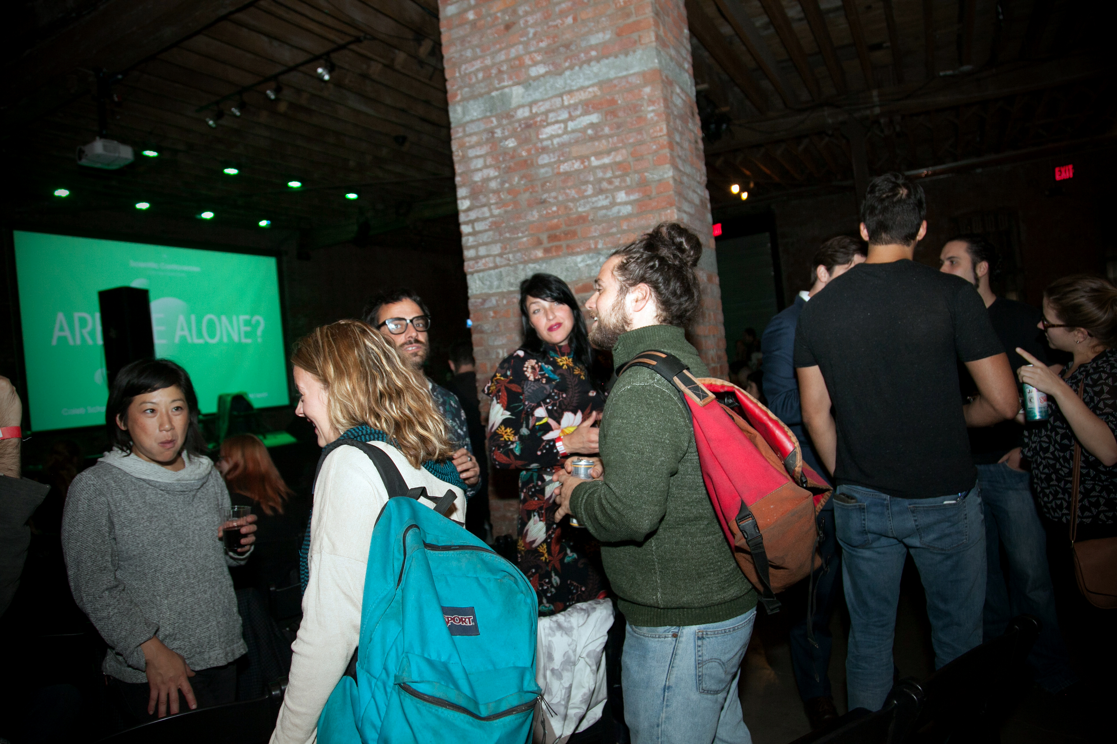 A dozen or so people in a darkened room talking