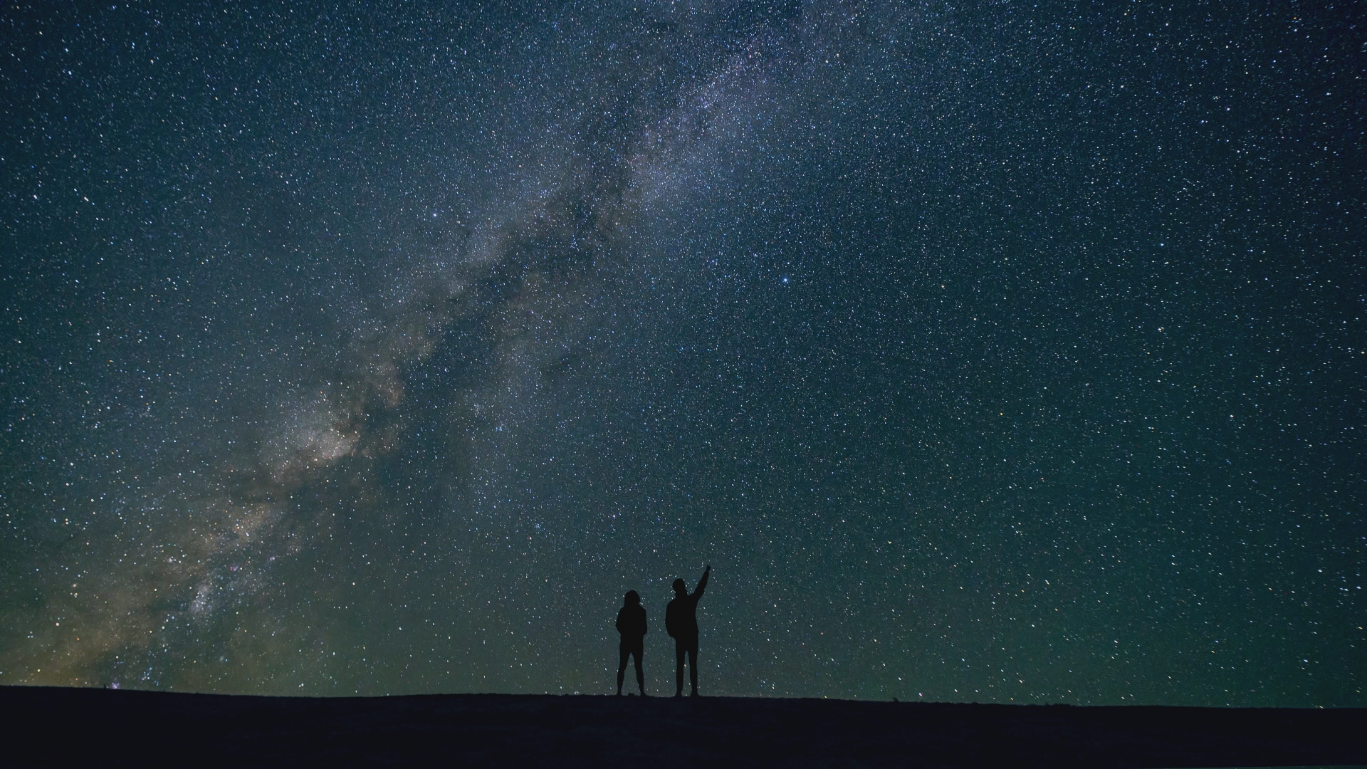 Two people pointing to the night sky