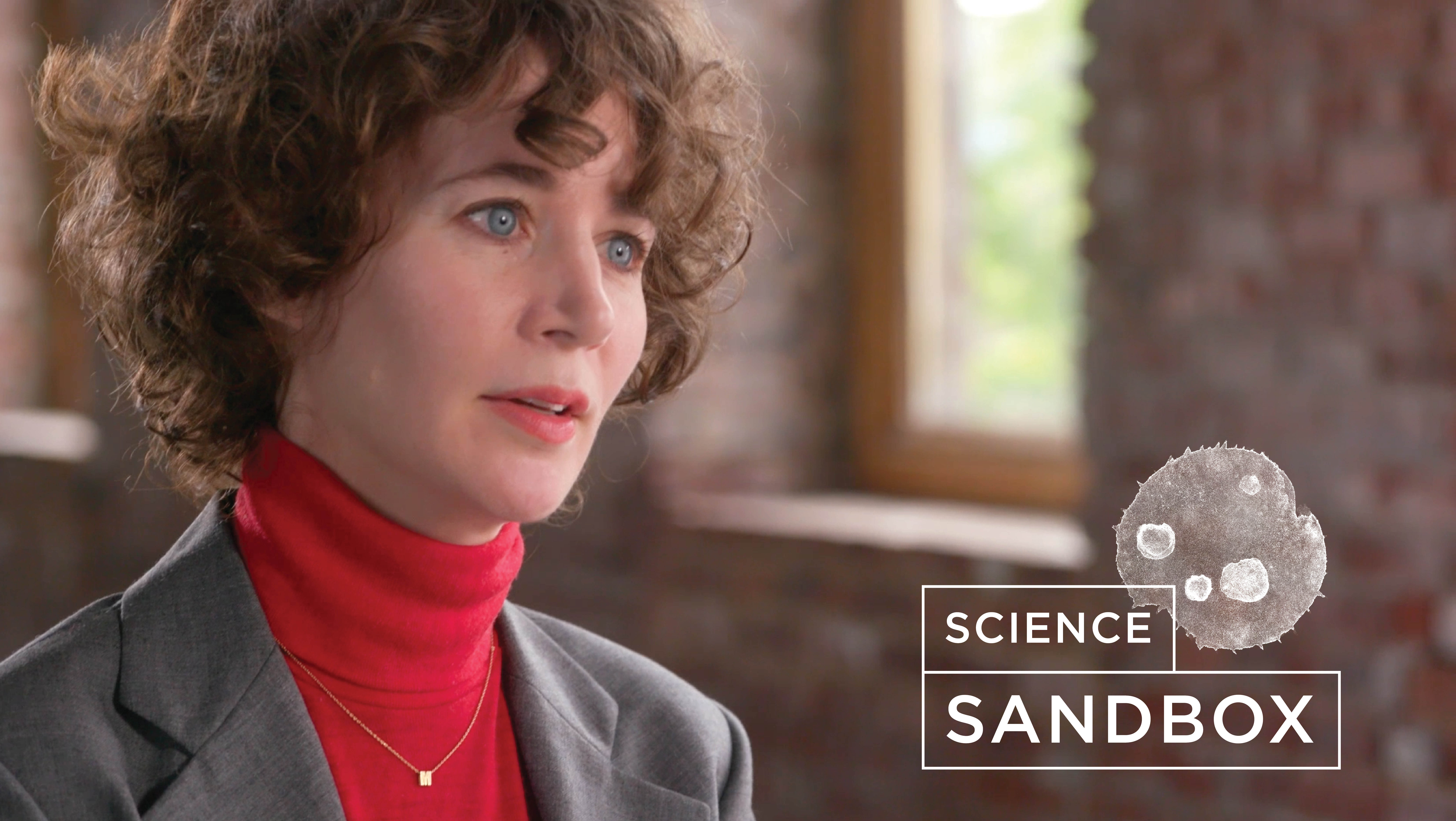 Miranda July talking in an empty hallway with the Science Sandbox logo pasted next to her