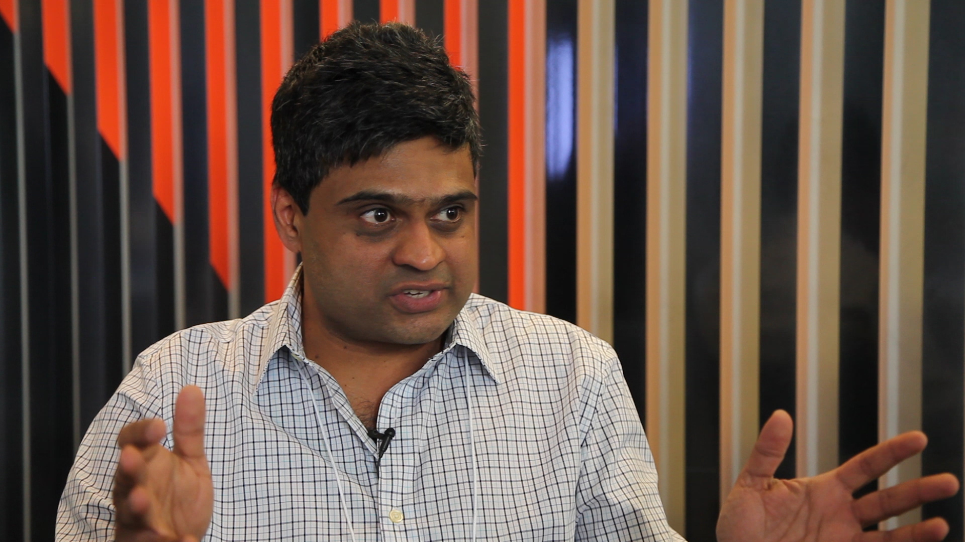 Ashvin Vishwanath talking in front of a wall with wooden slats