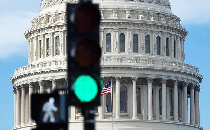 A traffic light in front of the dome of capitol building