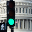 A traffic light in front of the dome of capitol building