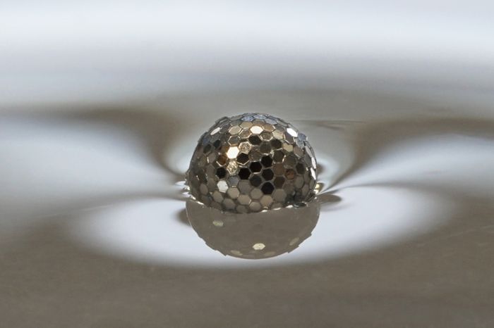 What looks like a floating disco ball is actually a ‘liquid marble’ formed from a water droplet coated in hexagonal plastic particles
