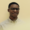 Headshot of Daniel Alabi - Black man in stripe collared shirt with glasses on