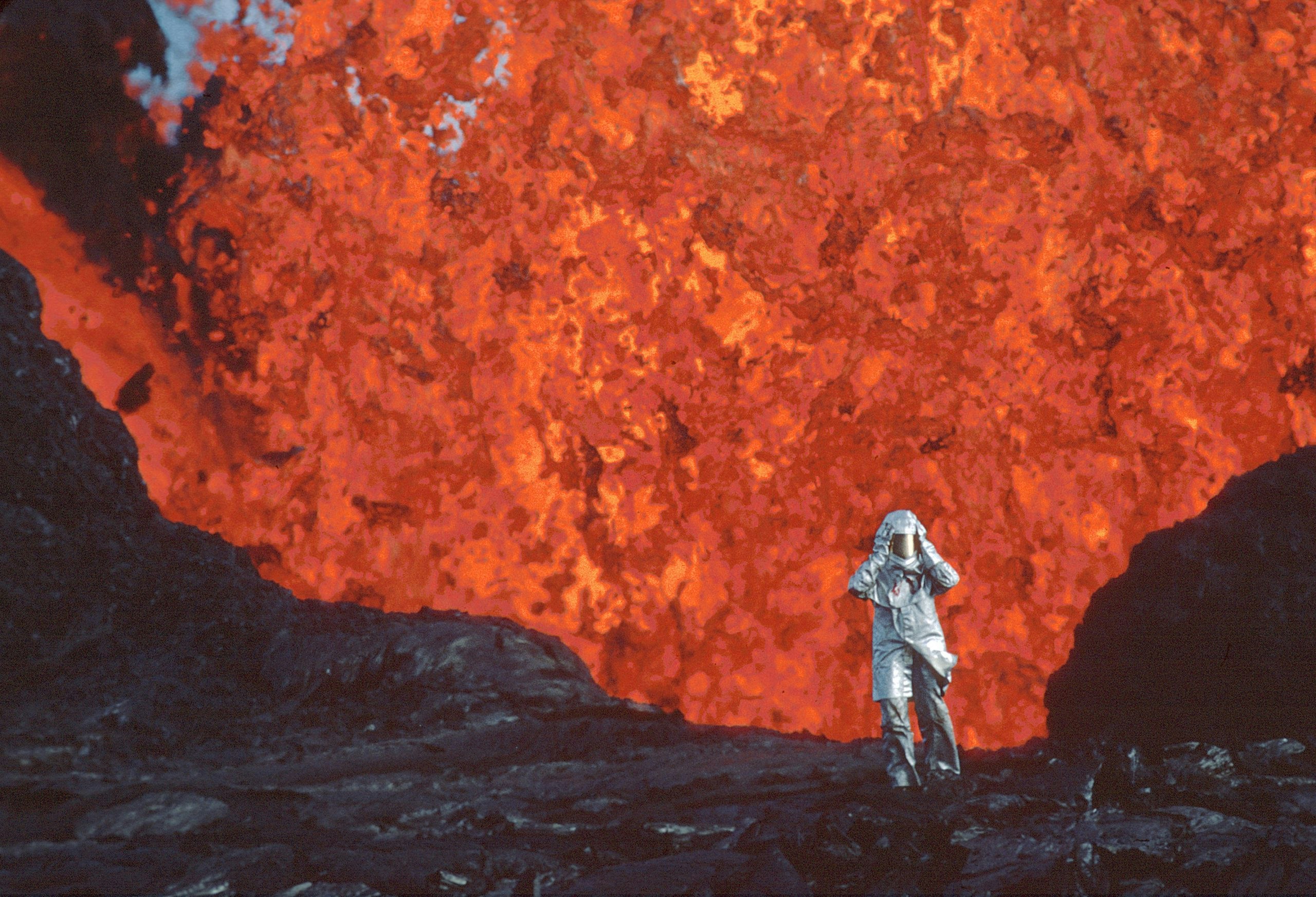 Person in silver suit in front of lava