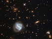 乍一看，这幅图像主要是由画面左下角漩涡的明亮光芒所支配。然而，这个星系远不是这里最有趣的景象，它背后是一个星系团。星系在空间中不是随机分布的；它们聚集在一起，被不屈不挠的重力之手聚集起来，形成群体和集群。银河系是本星系团的成员，本星系团是处女座星团的一部分，而处女座星系团又是10万星系强的拉尼亚凯亚超星系团的一个组成部分。在这张照片中看到的星系团被称为SDSS J0333+0651。这样的星团可以帮助天文学家了解遥远的宇宙，也就是早期宇宙。SDSS J0333+0651是研究远飞星系恒星形成的一部分。恒星形成区通常并不很大，最多延伸数百光年，所以望远镜很难在一定距离上分辨它们。即使使用最灵敏和最高分辨率的相机，哈勃望远镜也无法分辨非常遥远的恒星形成区域，因此天文学家使用了一种宇宙技巧：他们搜索星系团，而星系团的引力影响如此巨大，以至于他们扭曲了周围的时空。这种畸变就像一个透镜，放大了星系团后面很远的星系的光线，并产生了像这张图片中间左边看到的那样的细长弧线。