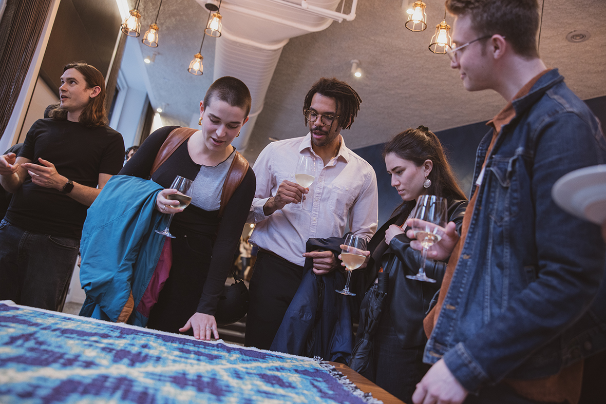 People standing around a table with a tapestry on it