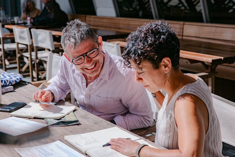 A photo of two people talking and writing.