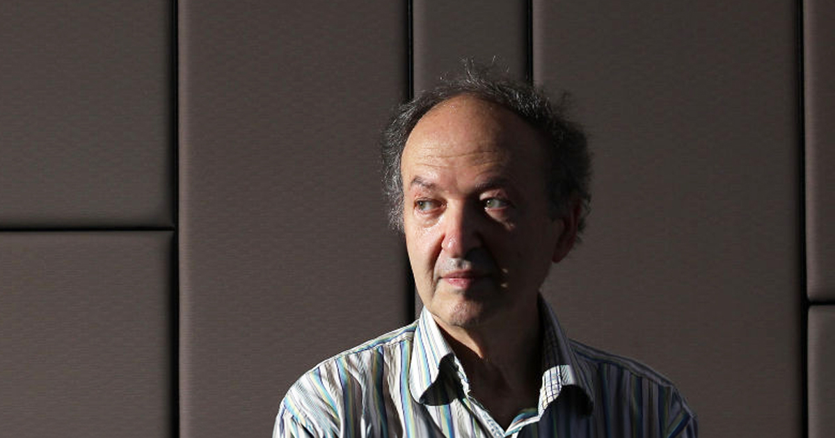 Portrait of George Lusztig in front of a brown backdrop.